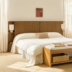 a bed with white sheets and pillows next to a wooden headboard in a bedroom