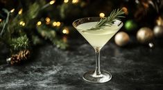 a martini glass filled with white wine and garnished with rosemary sprigs