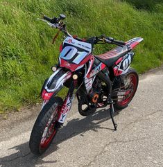 a red and white motorcycle parked on the side of a road next to green grass