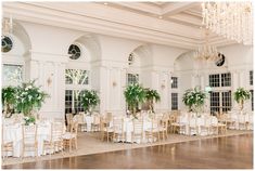 an elegant wedding reception with white linens and greenery on the tables, chandeliers and chairs