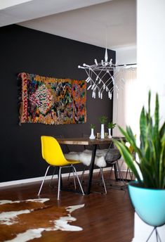 a dining room table with two chairs and a rug hanging on the wall above it