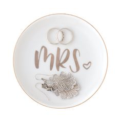 two wedding rings on a plate with the word mr and mrs spelled in cursive