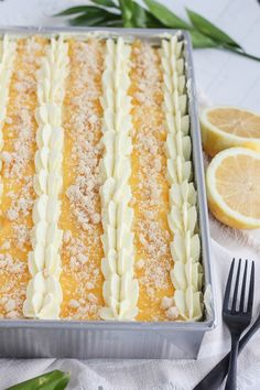 a close up of a cake in a pan on a table with lemons and utensils