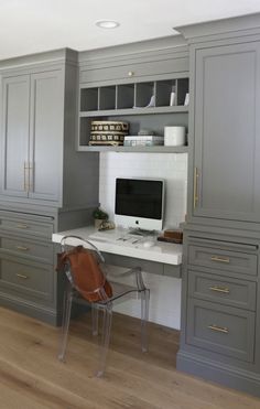 a desk with a computer on top of it in the middle of a room filled with gray cabinets