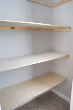 empty shelves in the corner of a room with carpeted flooring and white walls