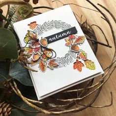 a close up of a card on a table with leaves and branches in the background