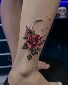 a woman's leg with a rose and moon tattoo on the lower part of her leg