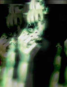 blurry photograph of woman's face and hands with green lights in the background