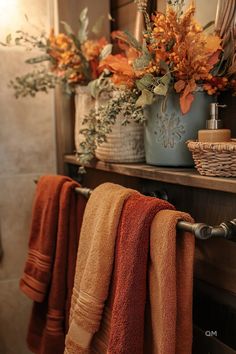 Cozy fall bathroom decor with warm-toned towels and vibrant autumn flowers in rustic containers. Perfect fall bathroom decoration ideas for your home. Bathrooms Decorated For Fall, Fall Decor In Bathroom, Cozy Fall Decor Bathroom, Rust And Blue Bathroom, Fall Decorations Bathroom, Antique Bathroom Decor Ideas, Brown And Orange Bathroom, Fall Decor Ideas For Bathroom, Fall Themed Bathroom