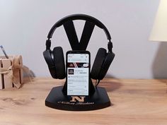 a cell phone and headphones are on a desk next to a wooden table with a lamp