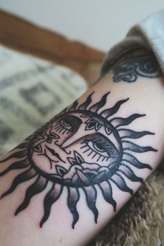 a tattoo on the arm of a person with sun and moon designs around it's eyes