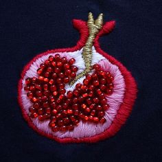 an embroidered pomegranate on a black shirt with red beads and sequins