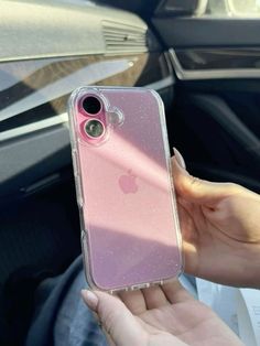 a person holding up a pink iphone case in their hand while sitting in a car