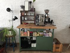 a coffee bar with lots of items on the counter and potted plants next to it