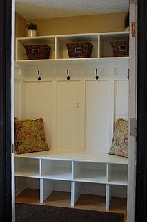 an entry way with white shelves and baskets on the top shelf, filled with pillows