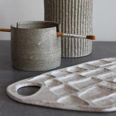 two gray vases sitting on top of a table next to a white spatula