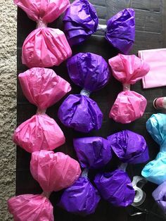 there are many bags of candy on the floor next to each other and one bag is wrapped in pink and purple tissue paper