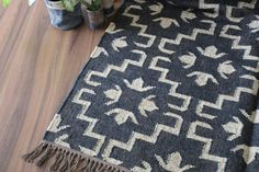 a black and white rug on the floor next to vases with flowers in them