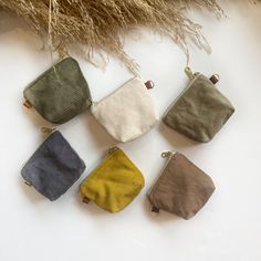 six small purses sitting next to each other on a white surface with dried grass in the background