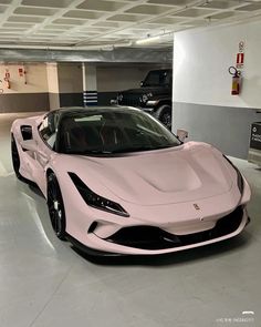 a pink sports car is parked in a parking garage with two other cars behind it