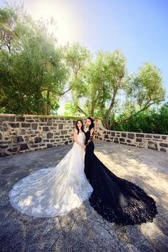 the newly married couple pose for a photo in front of some stone walls and trees