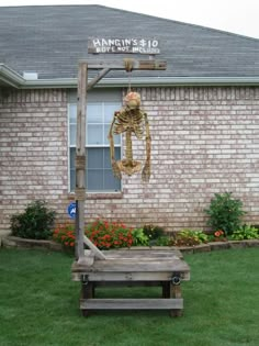 a wooden bench sitting in front of a brick building with a skeleton hanging from it