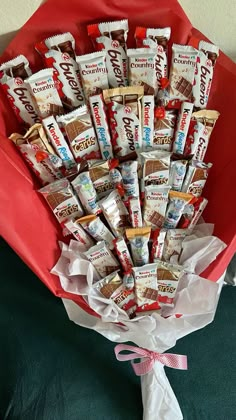 a bunch of candy bars in a red paper bouquet on a green tablecloth with pink ribbon