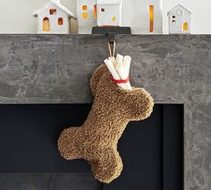 a stuffed animal is hanging from a fireplace mantel with candles on it and houses in the background