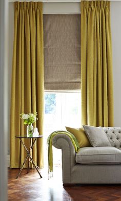 a couch sitting in front of a window covered in yellow curtains