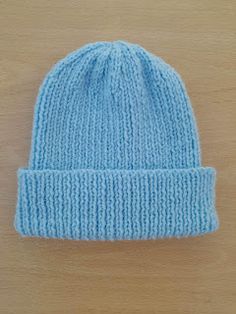 a blue knitted beanie sitting on top of a wooden table