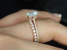 a woman's hand with a diamond ring on top of her finger and the other hand holding an engagement ring