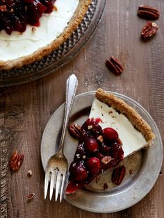 a piece of pie with cherries and pecans on a plate next to a fork