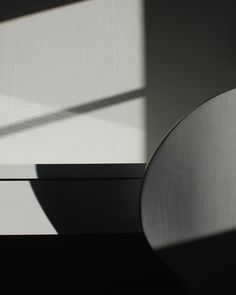 a black and white photo of the shadow of a round object on a table top