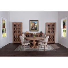 a dining room table with four chairs and a rug on the floor in front of it