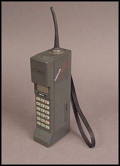 an old style cell phone with a cord attached to the front and back sides, on a gray background