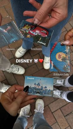 someone is holding up some disney cards on the ground with other people standing in front of them