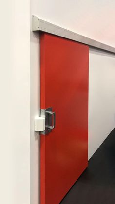 an open red door in the corner of a white room with black floor and walls