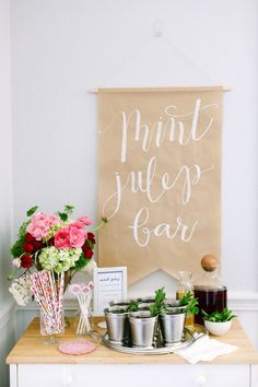 a table topped with cups and flowers next to a sign that says mint juice bar