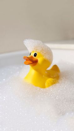 a yellow rubber duck sitting in a bathtub filled with foamy water and bubbles