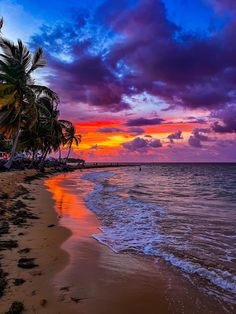 the sun is setting on the beach with palm trees