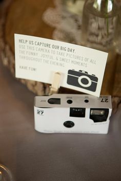 a small camera sitting on top of a table next to a sign that says help us capture our big day