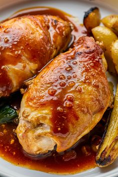 Roasted chicken thighs topped with a glossy sauce, served with roasted potatoes and green vegetables.