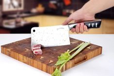 a person cutting up meat on top of a wooden cutting board next to a knife