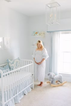 a pregnant woman standing next to her crib