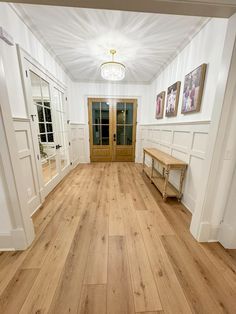 an empty room with white walls and wood floors, two benches on either side of the door