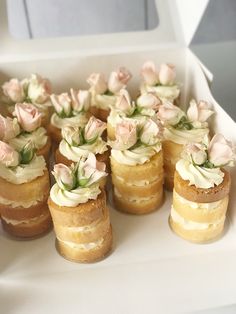 there are many small cakes with flowers on them in a white box and one is empty