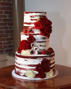 a three tiered cake with red and white flowers