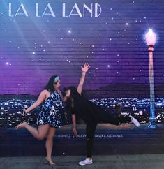 two people are posing in front of a wall with the words la la land on it