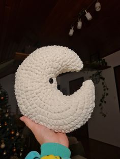 a person holding up a knitted white object with a smiley face drawn on it