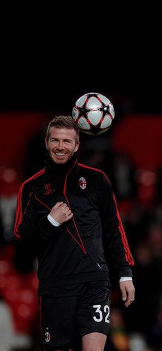 a man in black and red playing with a soccer ball on his head as he looks at the camera